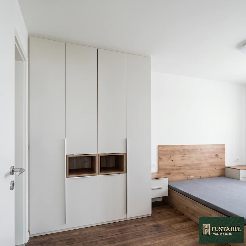 Armario empotrado a medida blanco mate con hornacinas decorativas en madera de roble y tiradores verticales.
